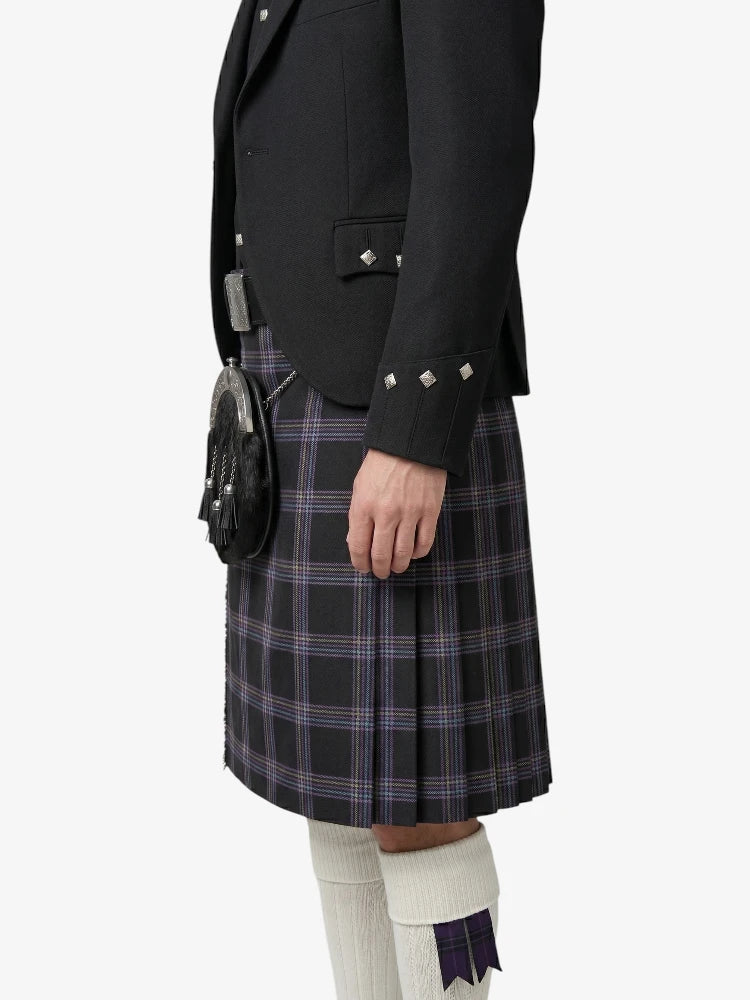 Person wearing a black jacket and plaid kilt on a white background