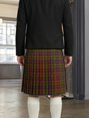 Person wearing a black jacket and plaid kilt indoors.