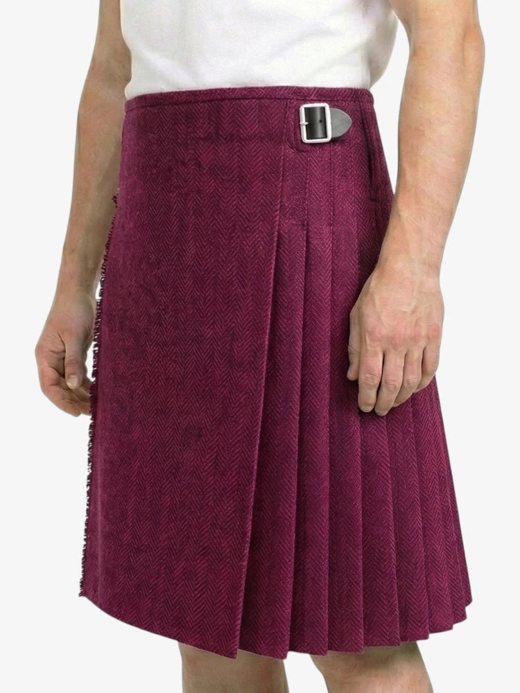 Person wearing a maroon pleated skirt with a belt on a white background