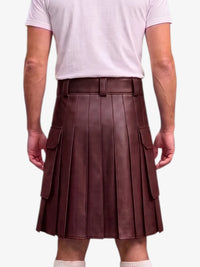 A person shown from the back wearing a dark brown pleated leather kilt with side cargo pockets, paired with a light pink t-shirt and white socks, against a plain light gray background.