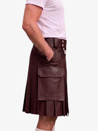 A dark green faux-leather kilt with pleated detailing, a front flap pocket, and a belt with silver-tone buttons, shown on a model wearing a light pink t-shirt against a white background.