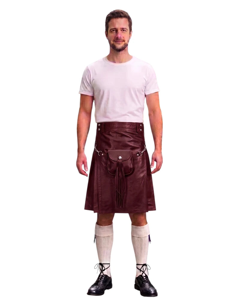 A man modeling a black faux-leather kilt with a matching black waist belt and pouch, paired with a white t-shirt, cream knee-high socks, and black lace-up shoes, against a plain white background.