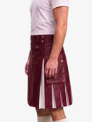 A man wearing a burgundy faux-leather kilt with pleated detailing, side pockets, and silver hardware, paired with a white t-shirt and beige socks, shown from the waist down against a light gray background.