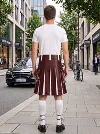A man viewed from behind wearing a white t-shirt and a dark red leather kilt with white vertical stripes, standing on a city sidewalk.