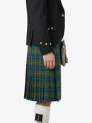 Person wearing a black jacket and green plaid kilt on a white background
