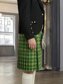 Person wearing a green plaid kilt with a black jacket indoors.