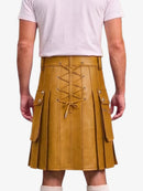 A mustard yellow faux-leather kilt with a lace-up front and side cargo pockets, shown on a model from the back wearing a light pink t-shirt.
