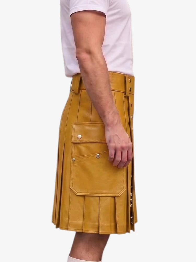 A mustard yellow faux-leather kilt with pleated detailing and flap pockets, shown on a model wearing a white t-shirt against a light gray background.