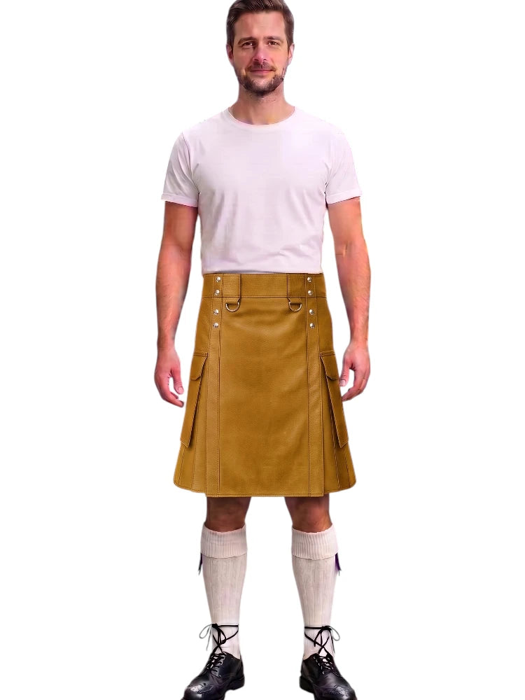 A man modeling a mustard yellow leather kilt with silver metal hardware, paired with a white t-shirt, white knee-high socks, and black lace-up shoes, against a plain white background.