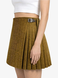 Brown pleated skirt with a silver buckle worn by a person on a white background