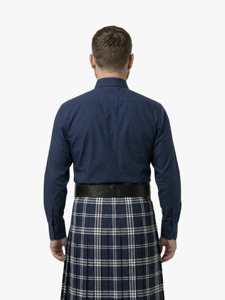 Man wearing a navy shirt and plaid kilt on a white background