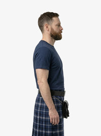 Man wearing a navy t-shirt and plaid kilt on a white background