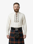 Man wearing a traditional Scottish kilt and shirt with a white background