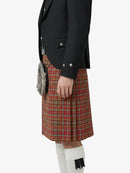 Person wearing a black jacket and red plaid kilt on a white background