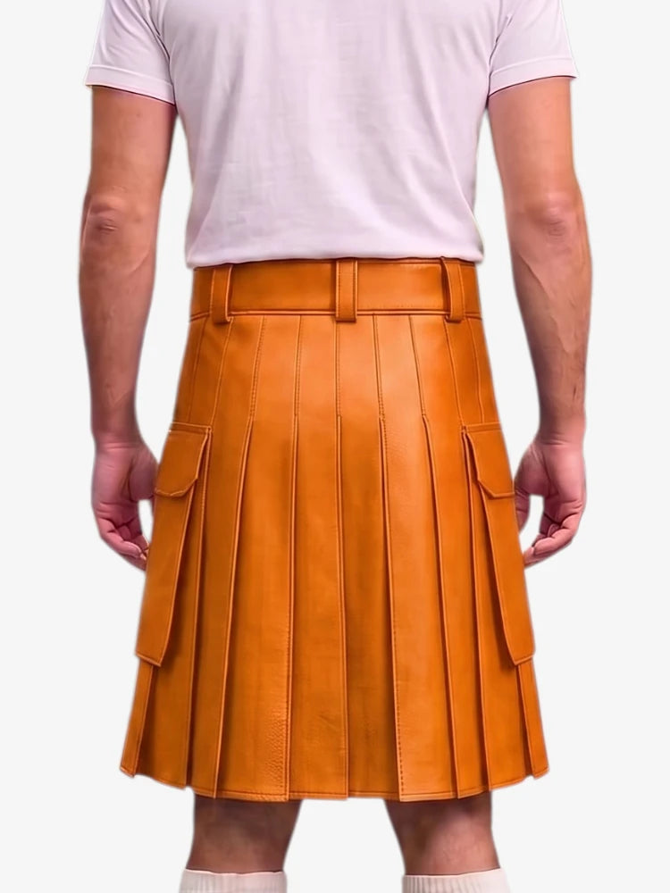 A person shown from the back wearing a mustard-orange pleated leather kilt with side cargo pockets, paired with a light pink t-shirt and white socks, against a plain light gray background.