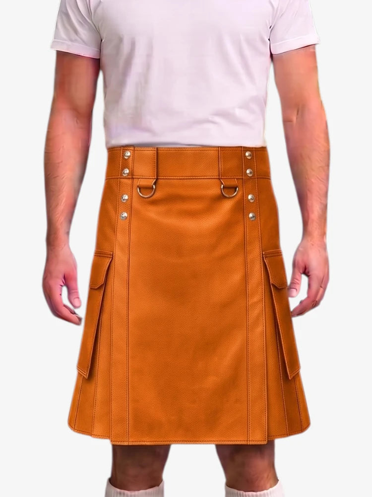 A person wearing a tan-brown leather kilt with silver-tone metal hardware and side cargo pockets, paired with a light pink t-shirt and white socks, shown against a plain light gray background.