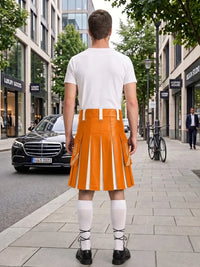 A man stands on a city sidewalk facing away from the camera, wearing a bright orange pleated kilt with white vertical stripes, a white t-shirt, white knee-high socks, and black shoes. Buildings, trees, a black Mercedes, and a bicycle are visible in the urban street setting.