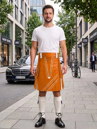 A man stands on a city sidewalk wearing a white crew-neck t-shirt and a bright orange kilt with white geometric stripe patterns. He is also wearing white knee-high socks and black leather shoes.