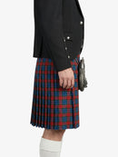 Person wearing a black jacket and red plaid kilt on a white background