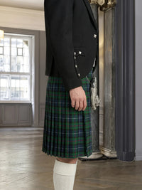 Person wearing a black jacket and green plaid kilt indoors.