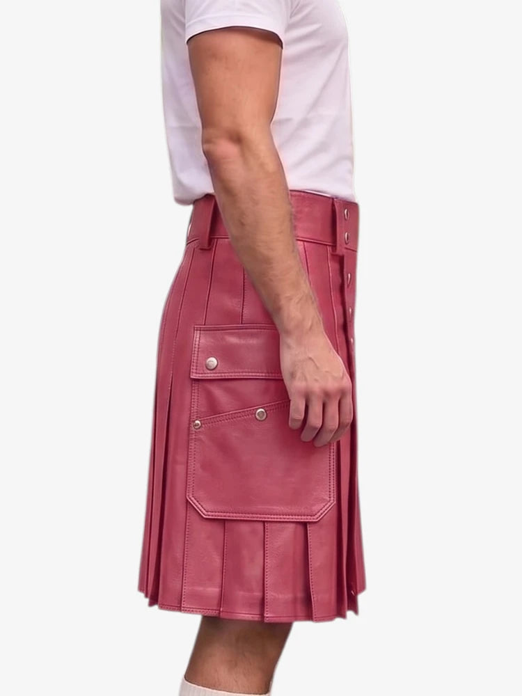 A person wearing a pink pleated leather kilt with silver snap buttons and a matching belt, paired with a white t-shirt, shown from the side against a light gray background.