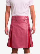 A model wearing a pink faux-leather kilt with pleated side panels, belt loops, and silver-tone hardware, paired with a white t-shirt against a light gray background.