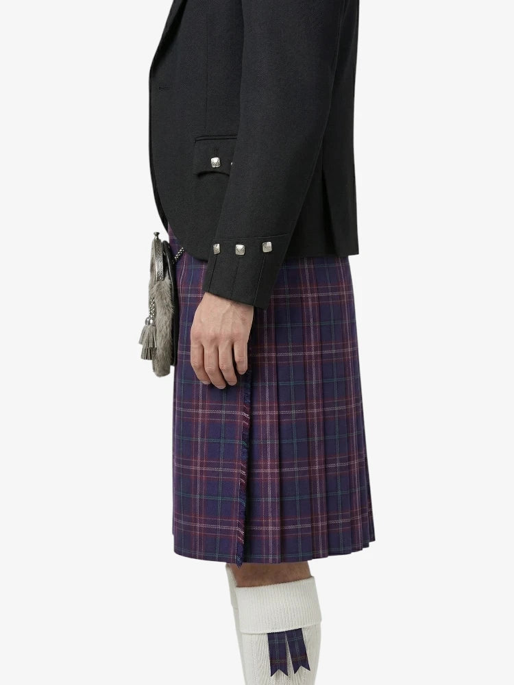 Person wearing a black blazer and plaid kilt on a white background