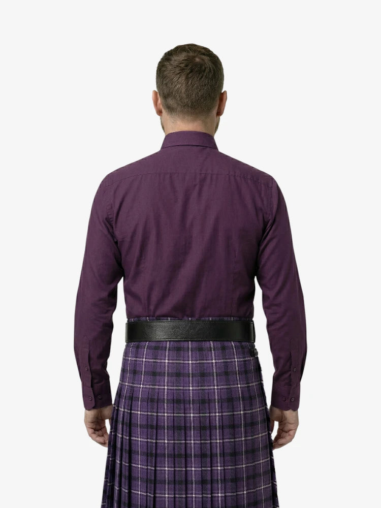 Man wearing a purple shirt and plaid kilt on a white background