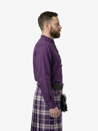 Man wearing a purple shirt and plaid kilt on a white background