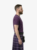 Man wearing a purple t-shirt and plaid kilt on a white background