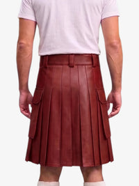 A person shown from the back wearing a dark reddish-brown pleated leather kilt with side cargo pockets, paired with a light pink t-shirt and white socks, against a plain light gray background.