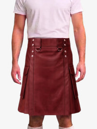A person wearing a burgundy faux-leather kilt with silver-tone metal hardware, a matching belt, and side flap pockets, paired with a light pink t-shirt against a plain white background.