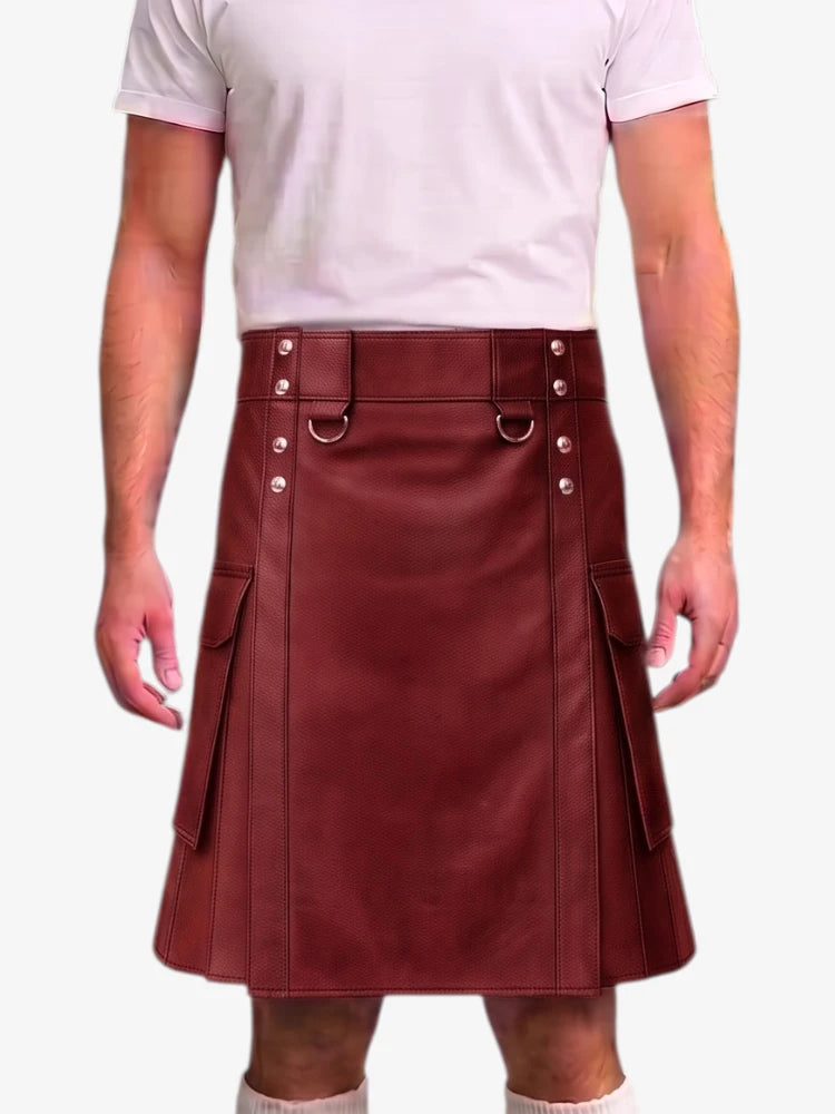 A person wearing a burgundy faux-leather kilt with silver-tone metal hardware, a matching belt, and side flap pockets, paired with a light pink t-shirt against a plain white background.