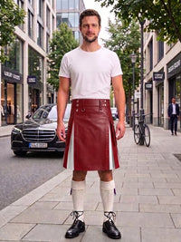 A man standing on a city sidewalk wearing a white crew-neck t-shirt and a red leather kilt with white side panels, paired with white knee-high socks and black leather shoes.