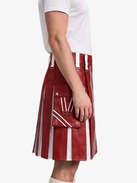 A model wearing a red and white vertically striped leather kilt with white leather suspenders and a matching red leather belt pouch, paired with a white t-shirt against a light gray background.