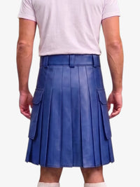 A person shown from the back wearing a blue pleated leather kilt with side flap pockets, paired with a light pink t-shirt and white socks, against a plain light gray background.