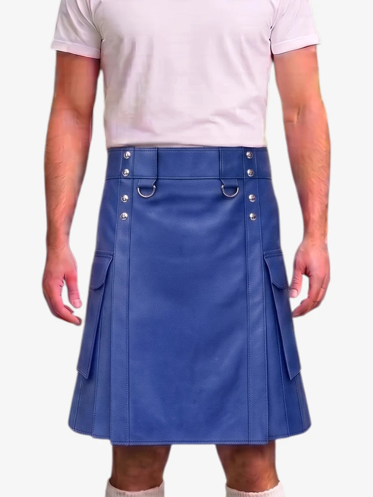 A man wearing a blue faux-leather kilt with silver-tone metal hardware and side cargo pockets, paired with a light pink t-shirt and white socks, against a plain white background.