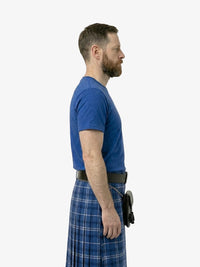 Man wearing a blue shirt and plaid kilt on a white background