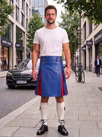 A man standing on a city sidewalk wearing a blue leather kilt with red side panels, a white t-shirt, white knee-high socks, and black shoes.