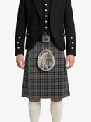 Person wearing a black jacket and gray plaid kilt with a tartan emblem on a white background