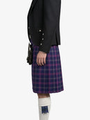 Person wearing a black jacket and purple plaid kilt on a white background