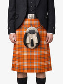 Person wearing a traditional Scottish kilt with an orange plaid pattern on a white background