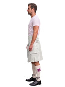 A man shown in profile wearing a white pleated kilt with multiple flap pockets, a light pink t-shirt, white socks with a purple accent, and black leather shoes, set against a plain white background.