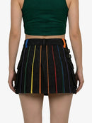 Person wearing a black pleated skirt with colorful stripes on a white background