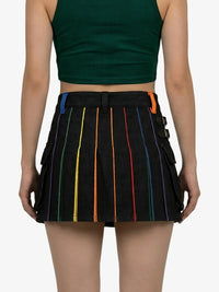 Person wearing a black pleated skirt with colorful stripes on a white background
