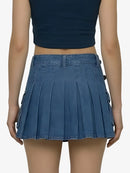 Person wearing a blue pleated skirt and navy top on a white background